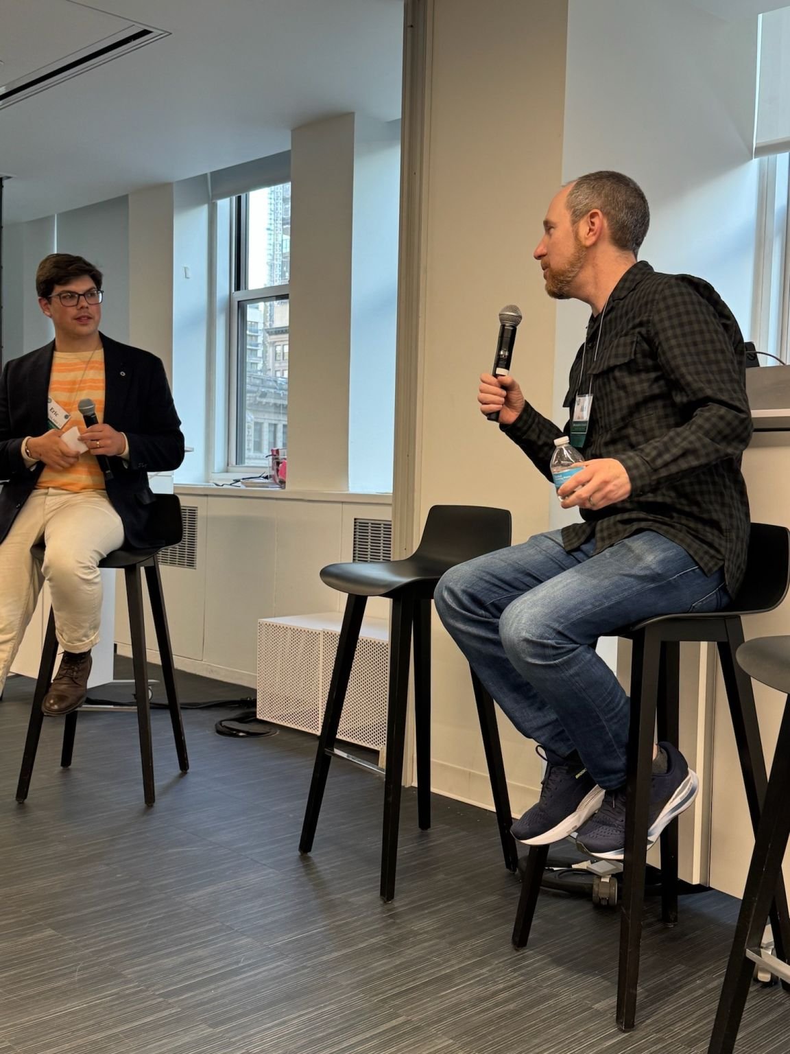 Eric Hirsh seated with a microphone in a fireside chat with Alan Stein